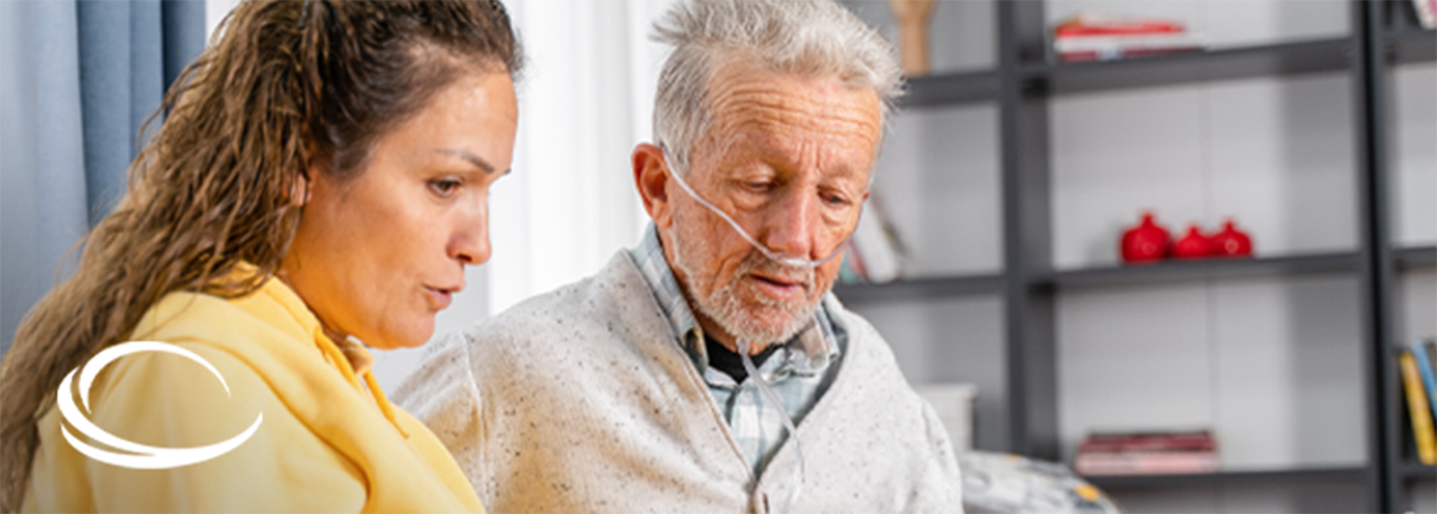 Female caregiver helping senior man with oxygen cannula at home