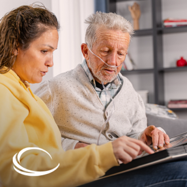 Female caregiver helping senior man with oxygen cannula at home