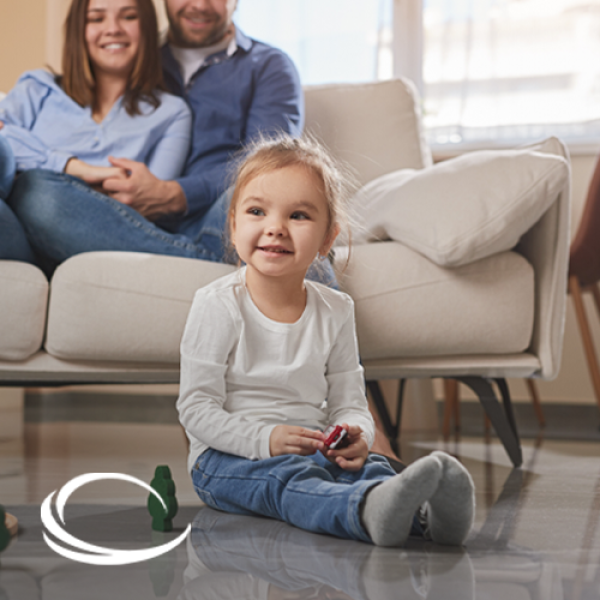 Girl sitting on the floor with her parents seated together on the couch above her