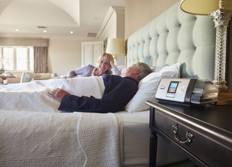 Photo of a couple on their bed with the AirCurve 10 VAuto next to them.