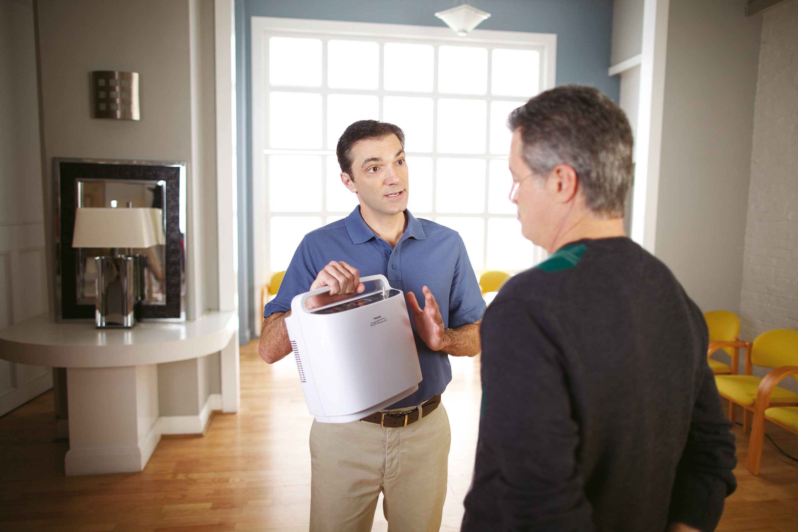 Photo of the SimplyGo Portable Oxygen Concentrator being presented by a person.