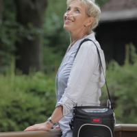 Photo of a woman carrying the Zen-O Portable Oxygen Concentrator outside. thumbnail