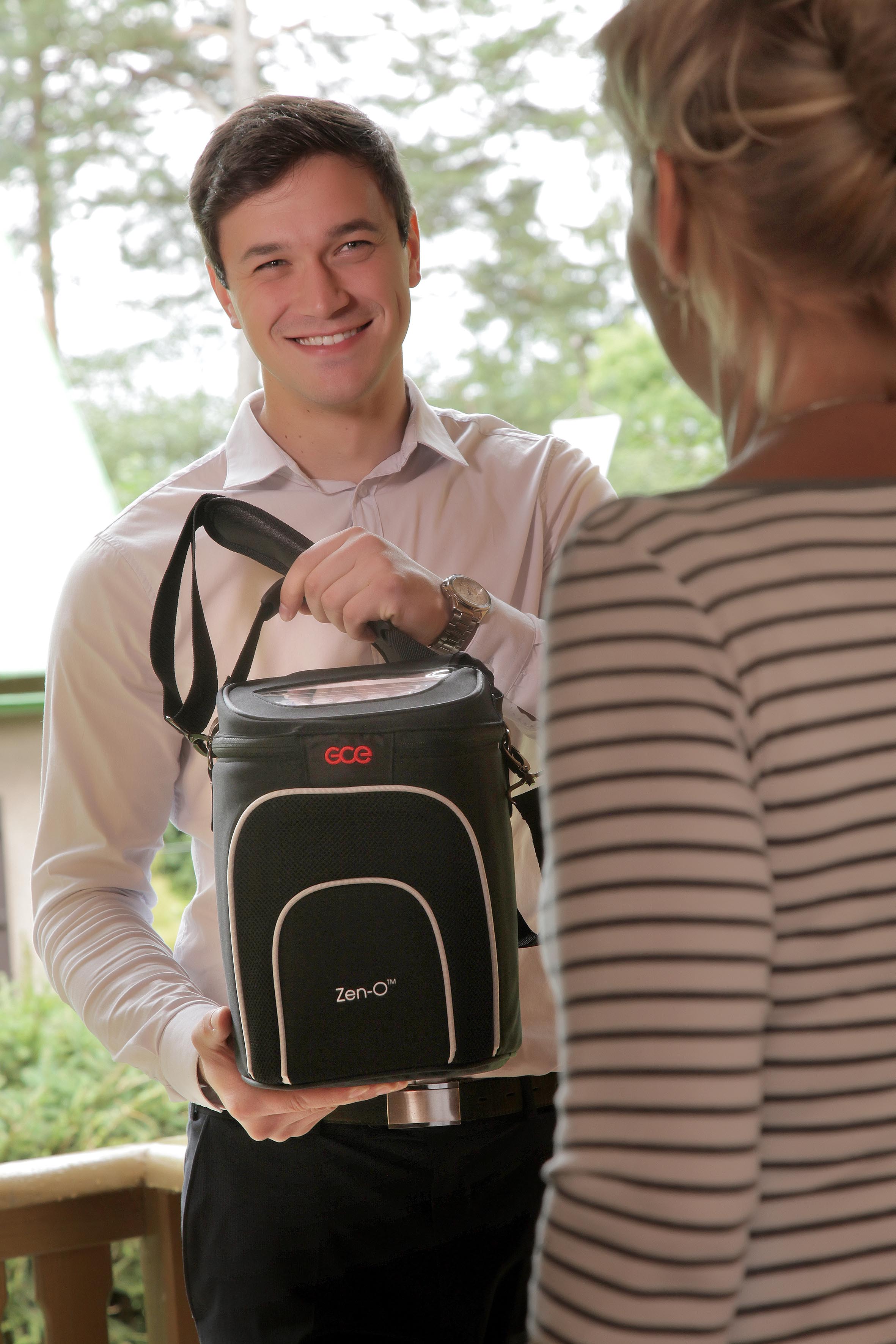 Zen-O Portable Oxygen Concentrator Exchange Photo of a man handing the Zen-O POC to a woman.